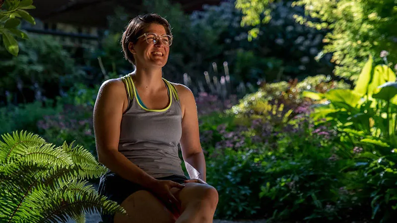 woman wearing sportswear sitting on stool in garden smiling