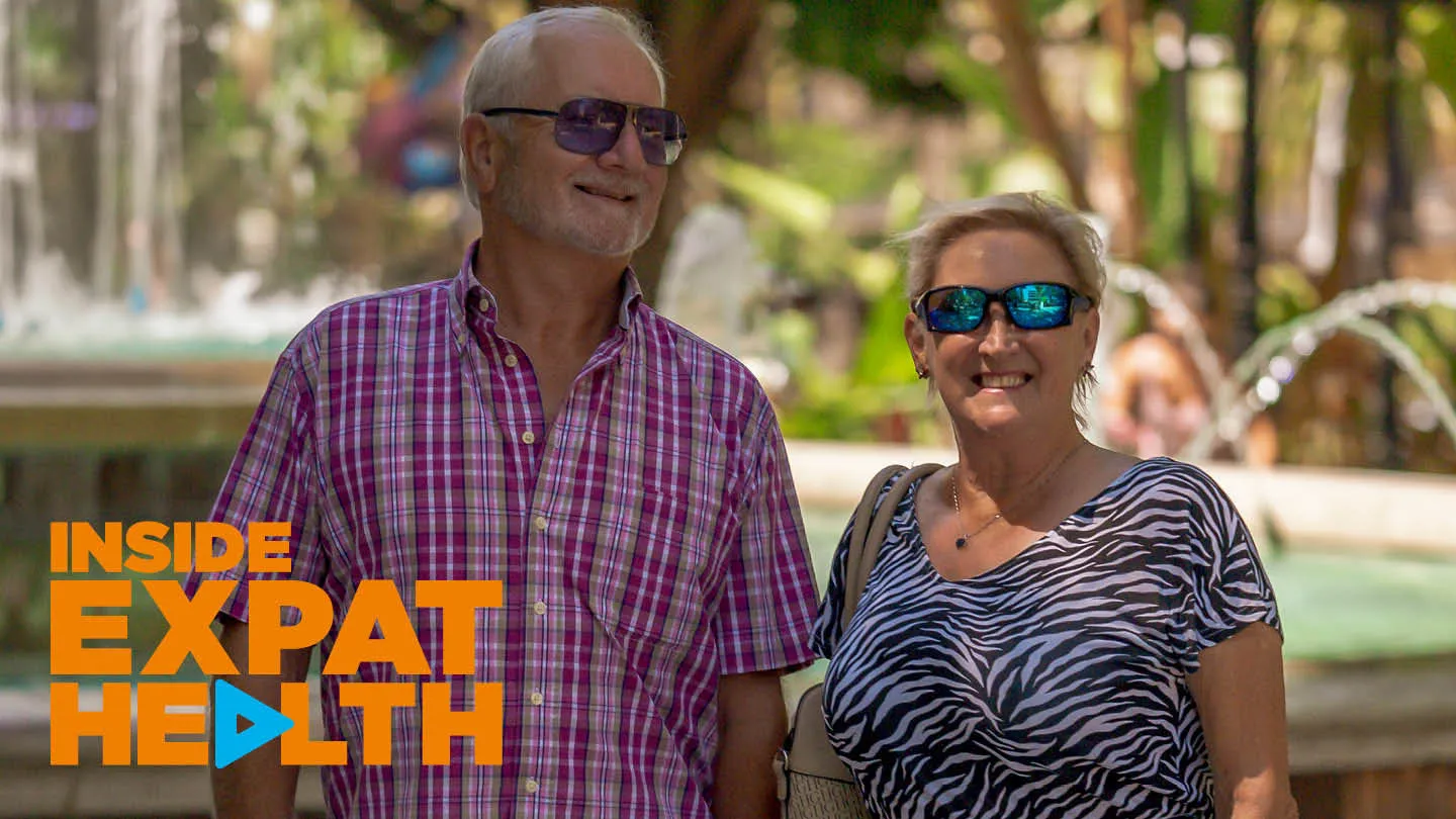Smiling British expat couple Dave and Barb walking hand in hand through a Spanish town in the sunshine