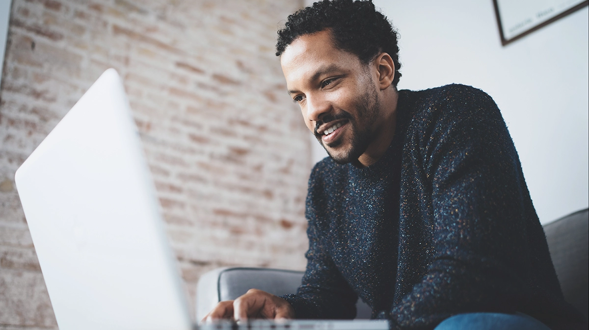 Smiling man reading from laptop screen