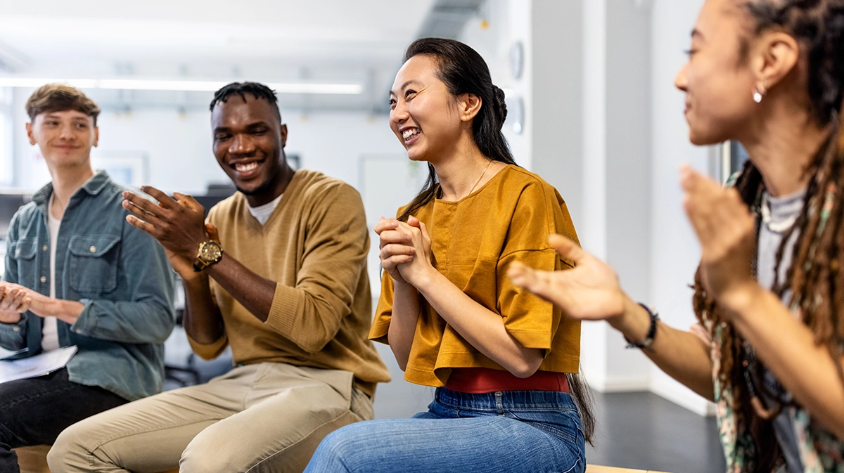 Group Of Business People Sitting In A Circle Clapping Hands In Meeting