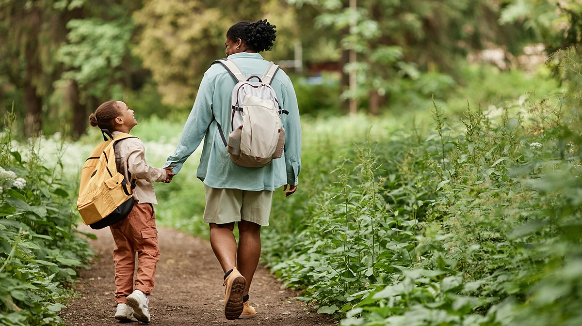 A mother and daughter walking on a path through the woods
