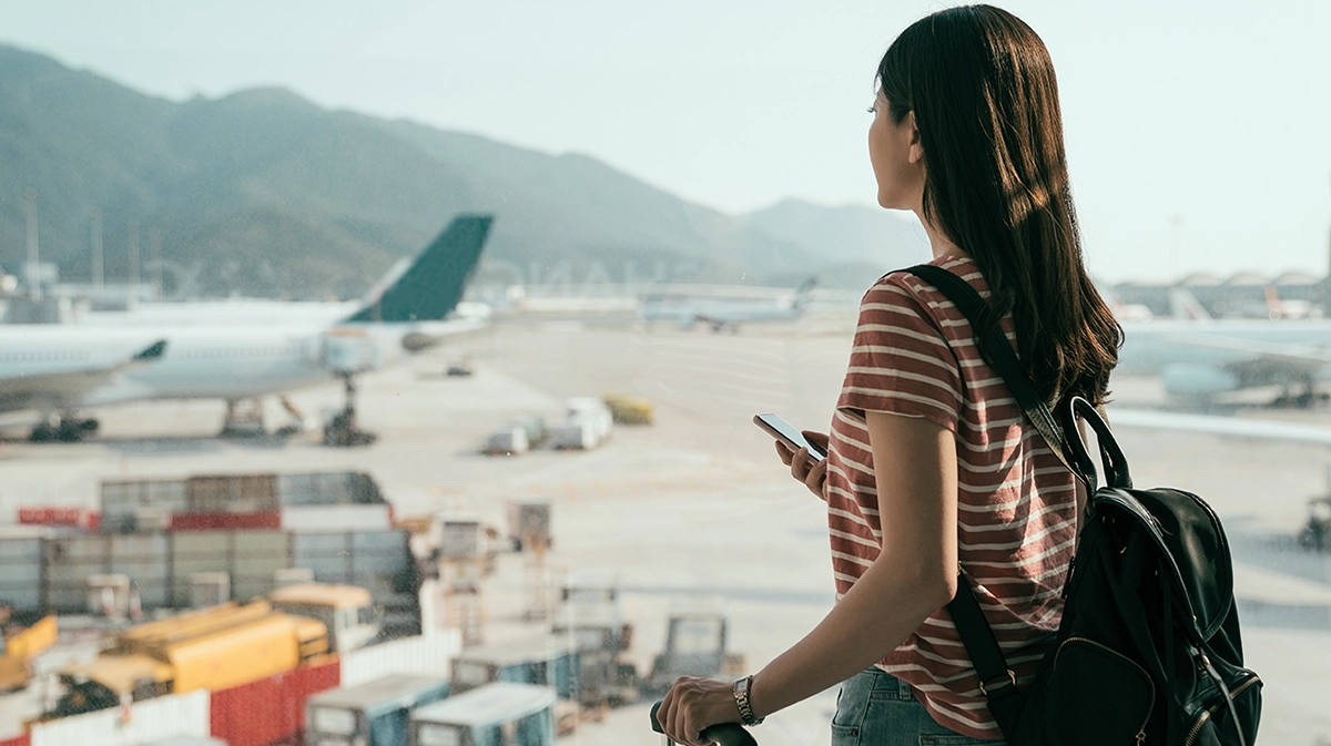 Woman travelling looks out window at airplane on runway